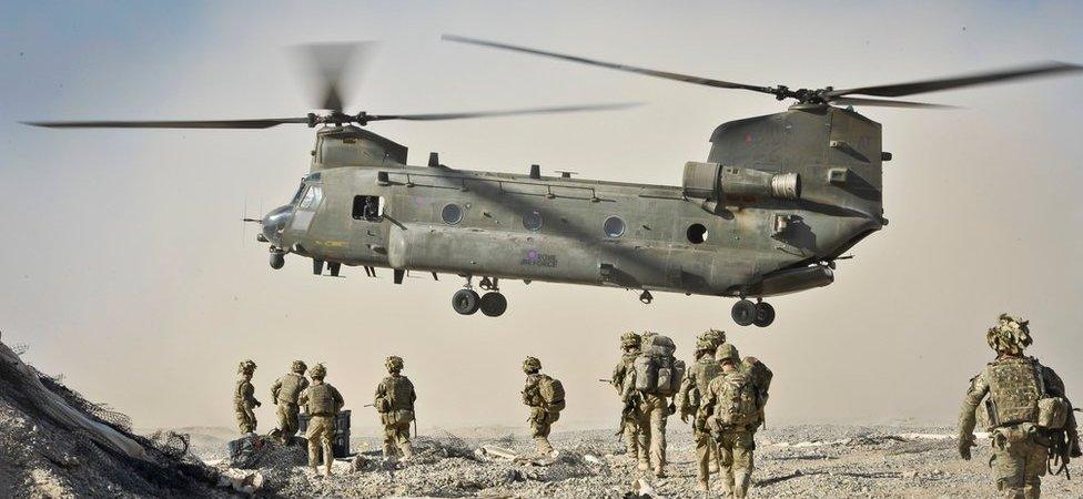 British troops approach an airborne Chinook aircraft in Afghanistan.