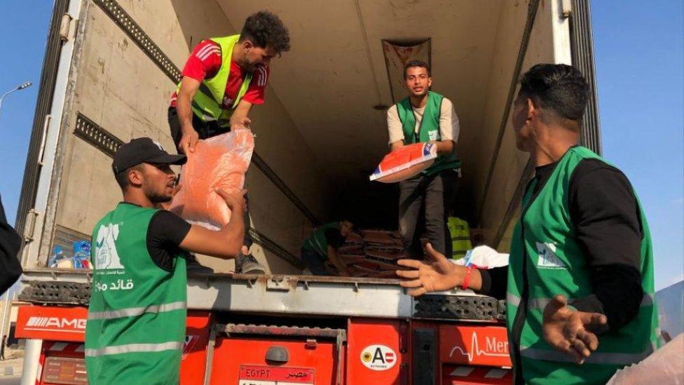 People load a humanitarian aid convoy for the Gaza Strip, parked in Arish, Egypt