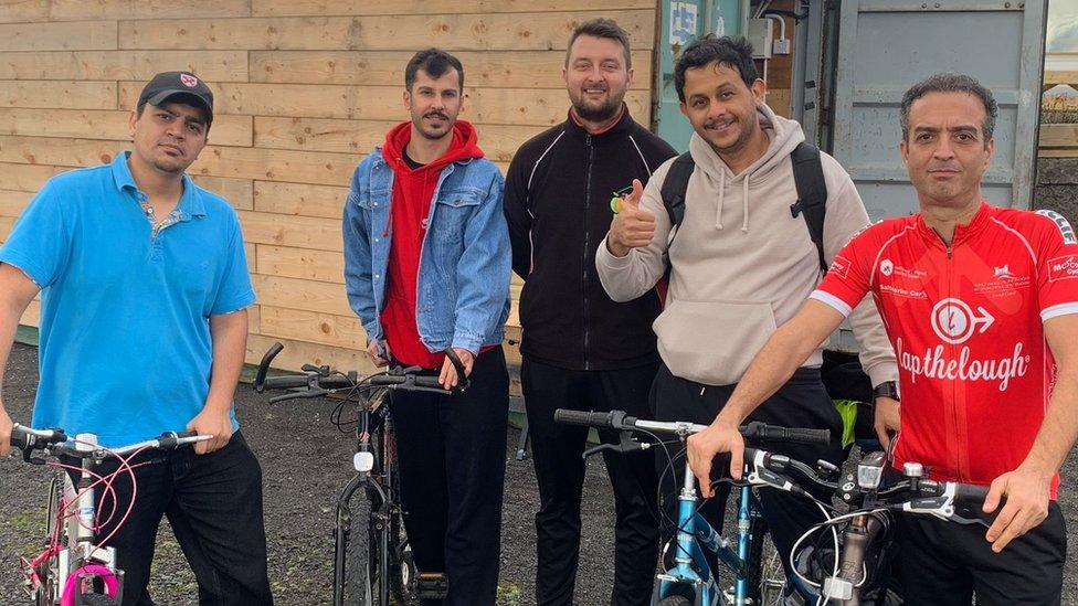 Five men involved in the bicycle repair project pose for a picture