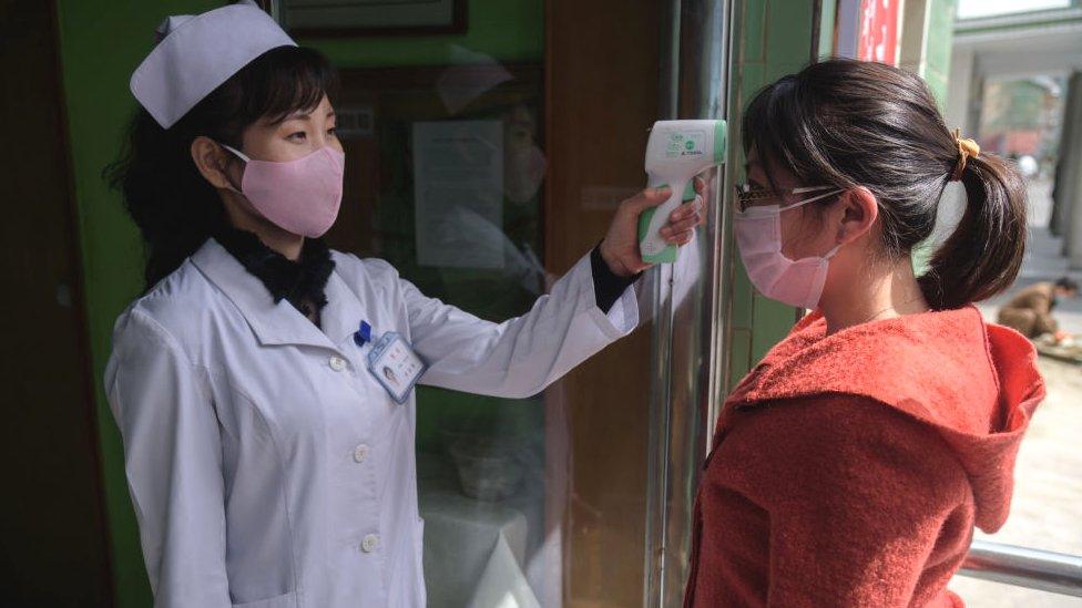 A health worker takes the temperature of a woman