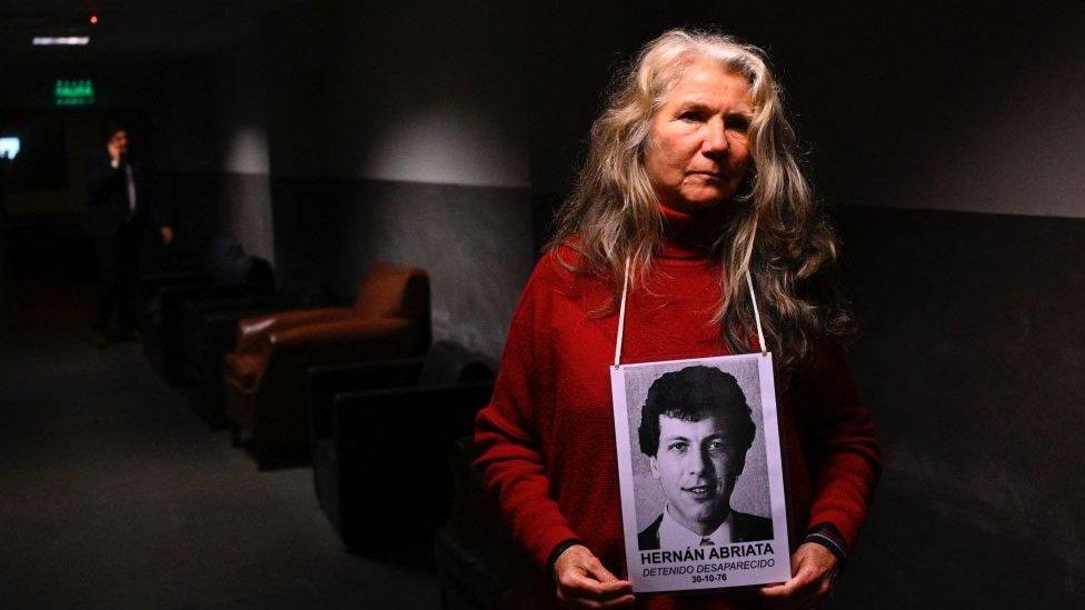 Monica Dittmar, the wife of missing Hernan Abriata, holds a picture of him as she waits for the beginning of the trial against Argentine former police officer Mario Sandoval over Abriata's disappearance at the federal courts in Buenos Aires, on September 14, 2022.