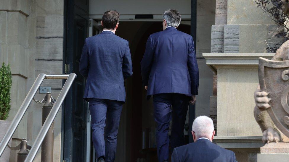 Simon Harris and an official enter Stormont Castle