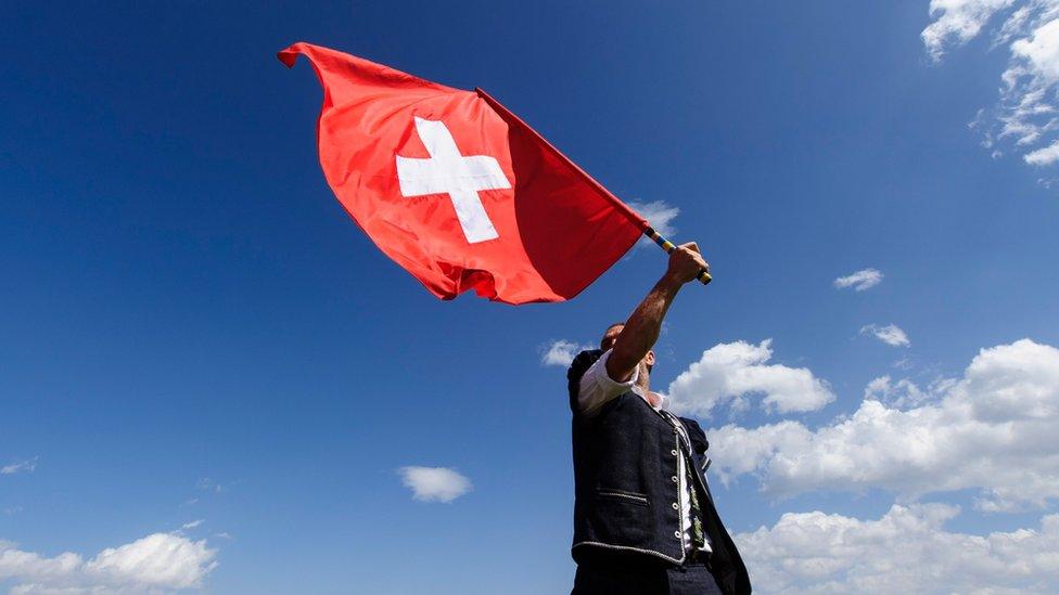 A man throws a Swiss flag on July 28, 2013 in Nendaz, Switzerland