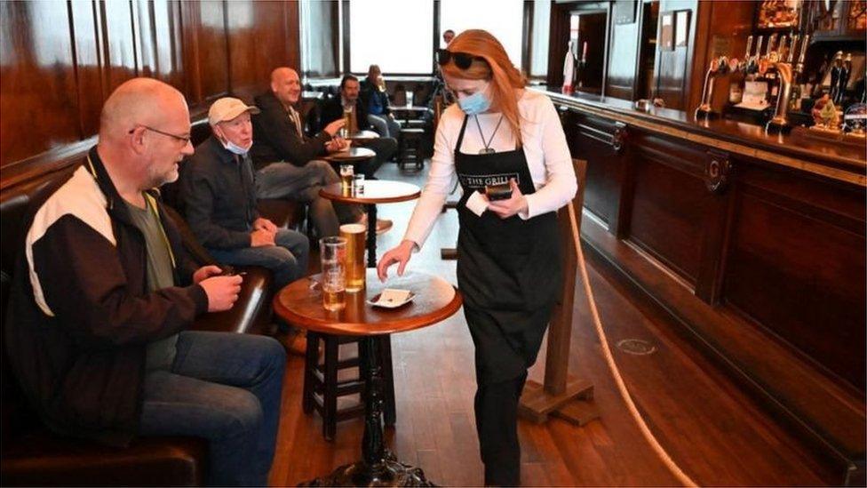 Bar worker in a pub with customers