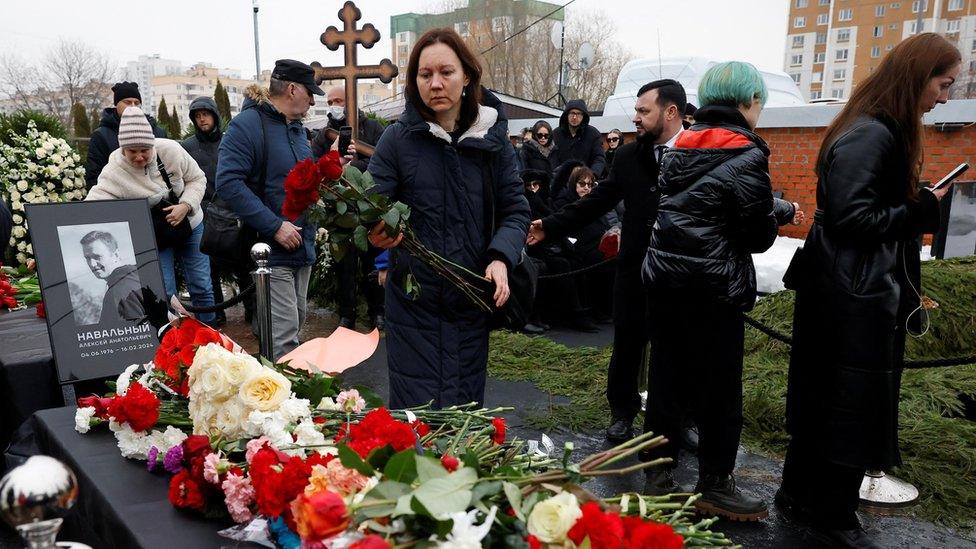 People lay flowers on Navalny's grave at Borisovskoye cemetery