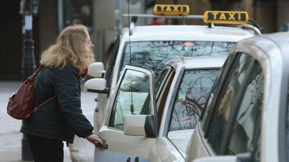 A woman prepares to climb into a taxi