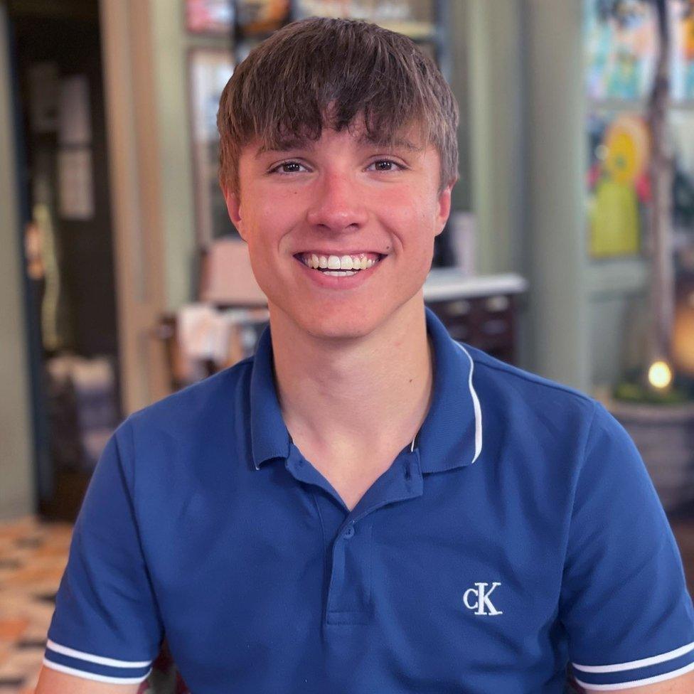 A picture of Barnaby Webber, who is wearing a blue polo shirt and smiling at the camera