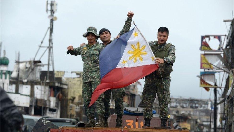 Philippine soldiers aboard their armoured personnel carrier celebrate after President Rodrigo Duterte declared Marawi City "liberated", inside the battle area of Bangolo in Marawi on October 17, 2017.