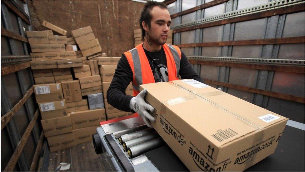 An Amazon worker loads a package on a truck