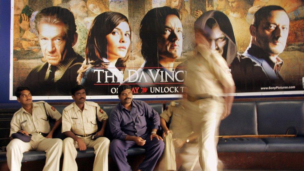 A group of policemen guard a poster of the Da Vinci code