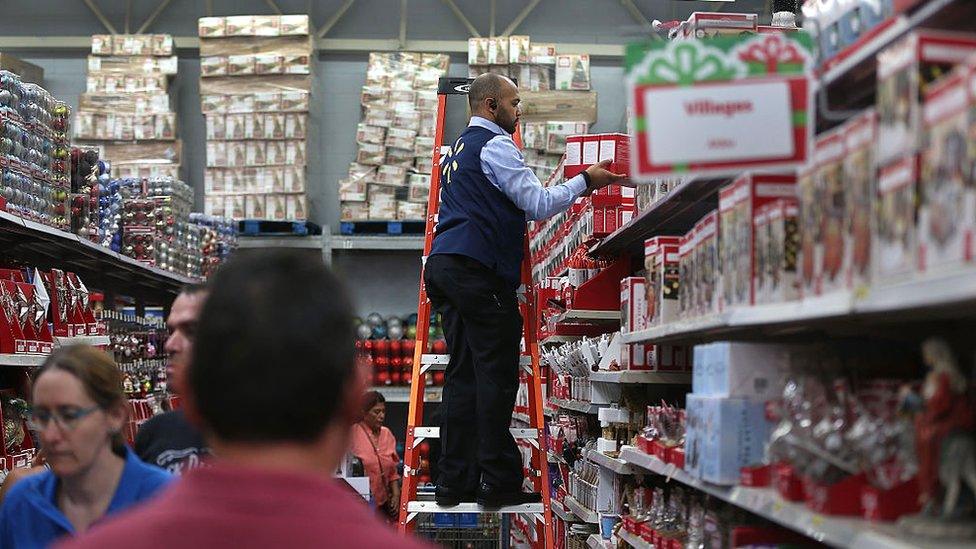 A Walmart employee stocks a Christmas shelf