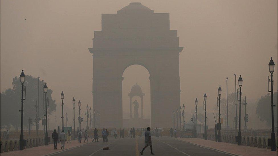 Pedestrians walk along a road near the India Gate amid heavy smog in New Delhi. Delhi's air quality remains "severe", accounting for 30 per cent of the PM2.5 pollution in the capital, Air Quality Index (AQI) at Noida (UP) is 529, 478 in Gurugram (Haryana) and 534 near Dhirpur, all in 'Severe' category. (Photo by Amarjeet Kumar Singh/SOPA Images/LightRocket via Getty Images)