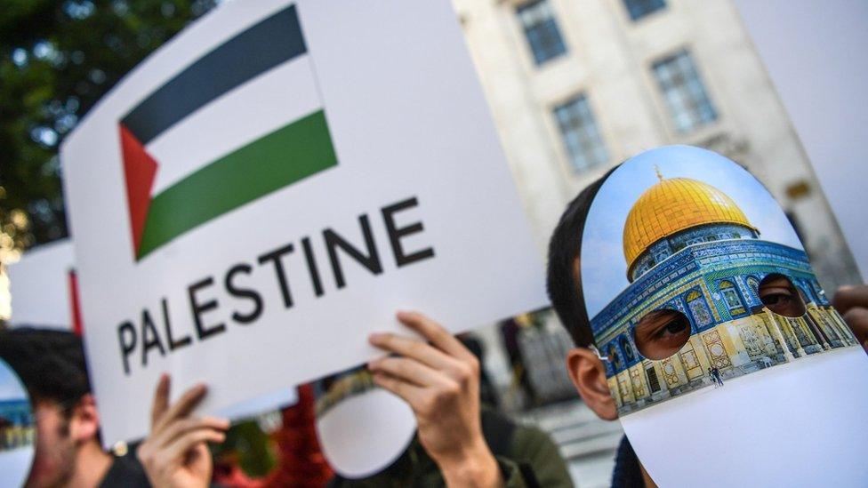 People wearing masks featuring Jerusalem's Dome of the Rock mosque gather outside the Organisation of Islamic Co-operation summit in Istanbul (13 December 2017)