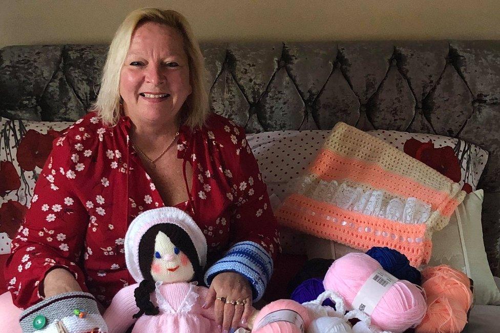 Susan Crossland surrounded by knitted items