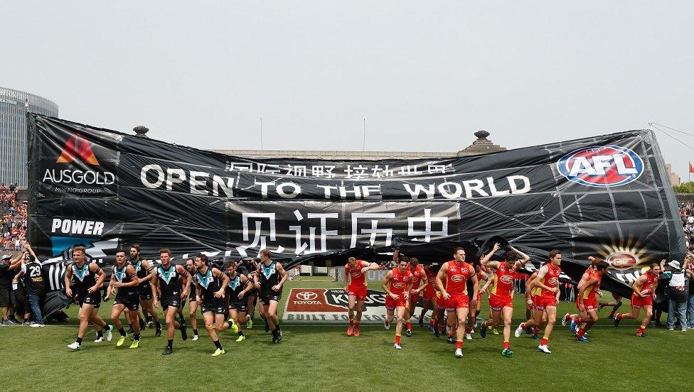 Players run through a banner before the match