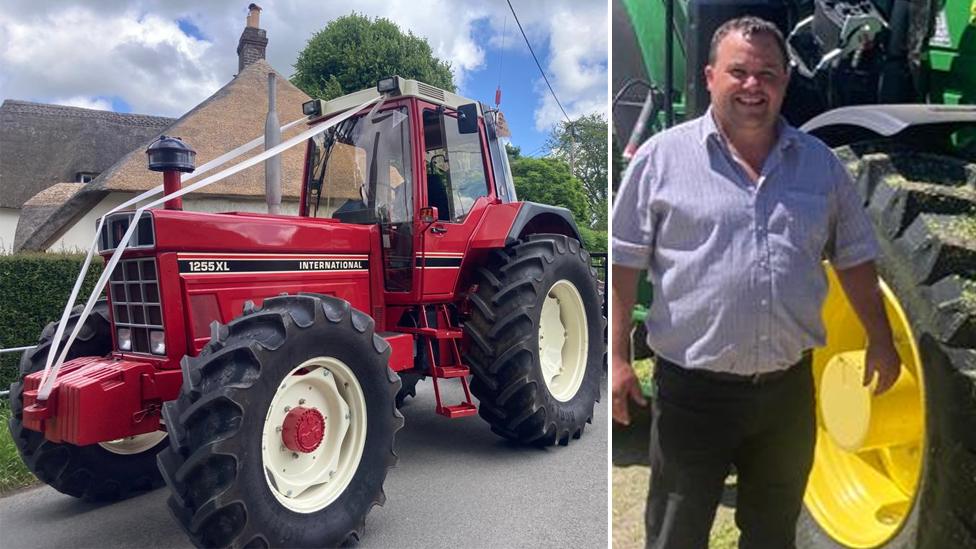 Red tractor and trailer decorated with white wedding ribbons, and Philip Trim standing next to a tractor wheel