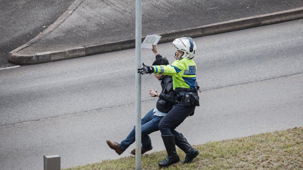 A student activist being detained by a traffic police officer