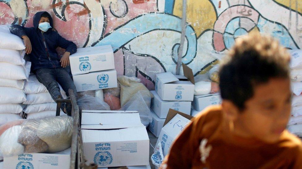 A Palestinian boy sits on a bag of flour at an aid distribution centre run by the United Nations Relief and Works Agency (Unrwa) in Gaza City (20 January 2021)