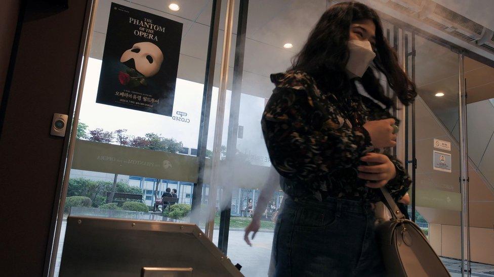 A woman walking through disinfectant "fog" in South Korea