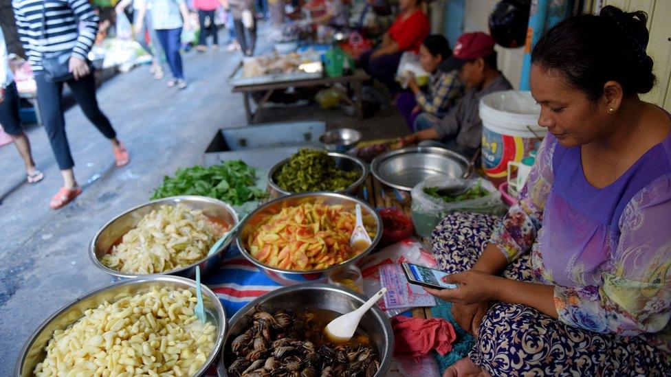 Woman on a smartphone at a market in Cambodia