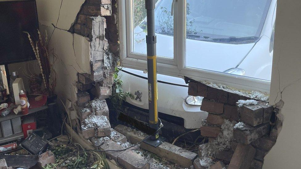 A destroyed house wall after a van crash