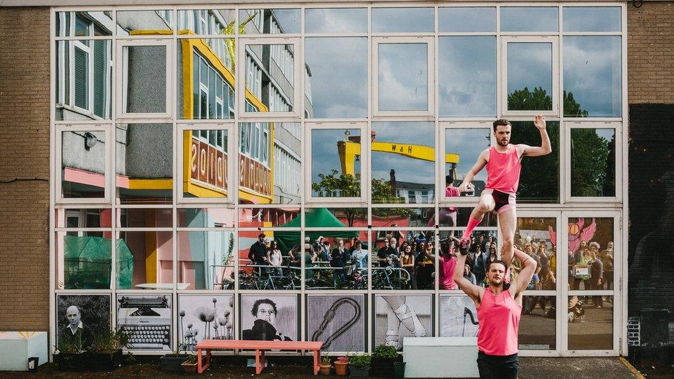 Trapeze artists perform to a crowd outside Vault Studios