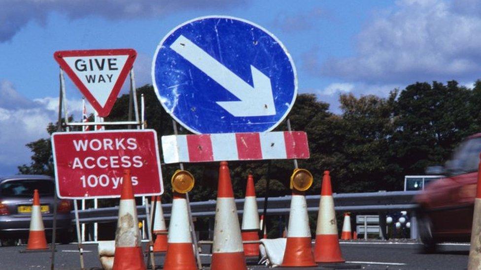 Car drives past a works access sign