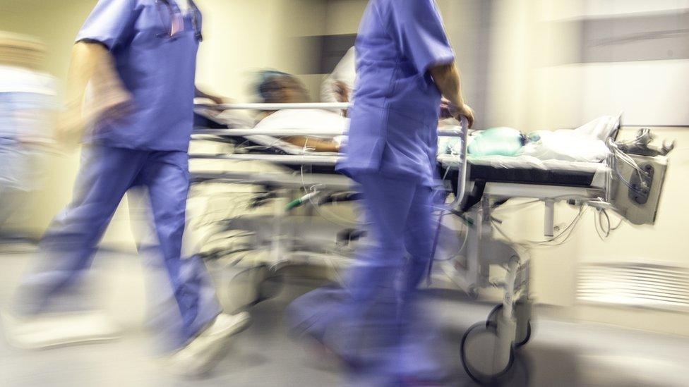 A patient on a trolley wheeled by two nurses