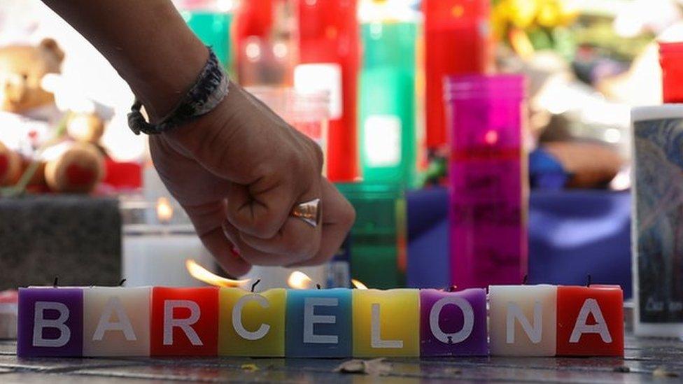 A man lights a candle in an impromptu memorial a day after a van crashed into pedestrians at Las Ramblas in Barcelona