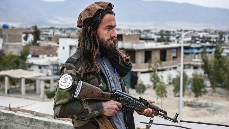 A Taliban guard mans a post on the roof top of the main gate of Laghman University in Mihtarlam