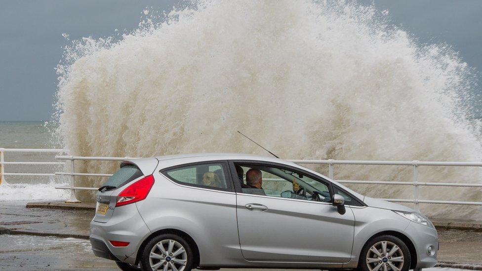 Car sat on the promenade with a huge wave