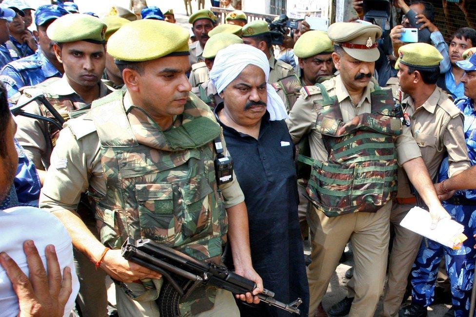 Police officers escort Atiq Ahmed, a former lawmaker in India's parliament, accused in several criminal cases, outside a court in Prayagraj, India, April 13, 2023.