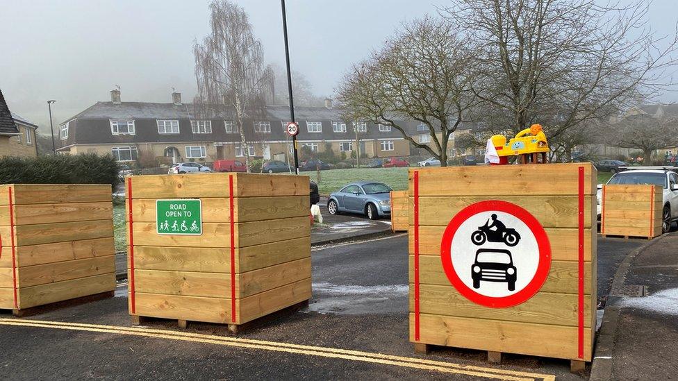 Planters with no traffic sign on a street with houses in the background