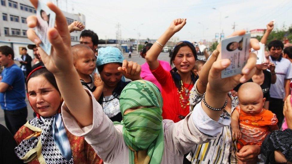 An Uighur woman holds the IDs of her relatives who are are currently detained, as she and others protest on a street in July, 2009