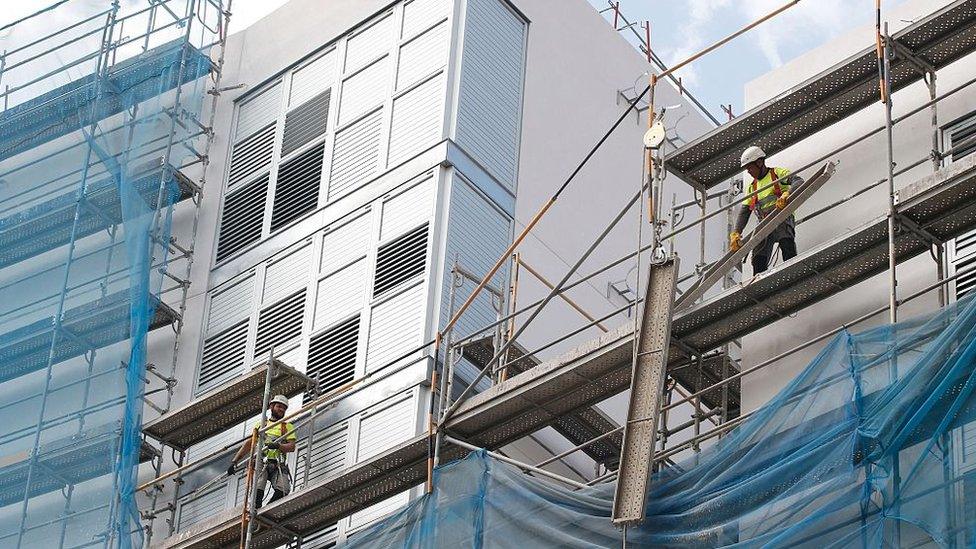 Worker disassemble scaffolding built along the facade of a building under construction in Barcelona