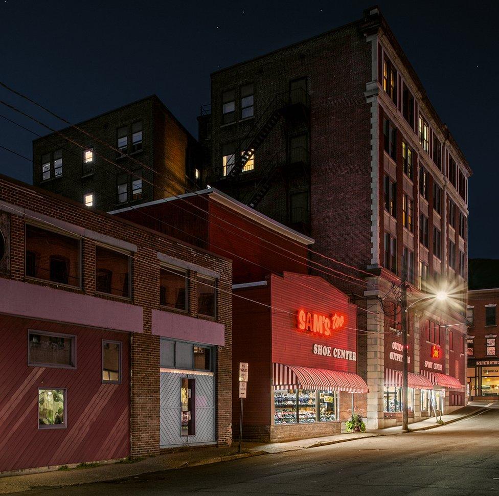 A night view of a shoe shop with a red neon sign