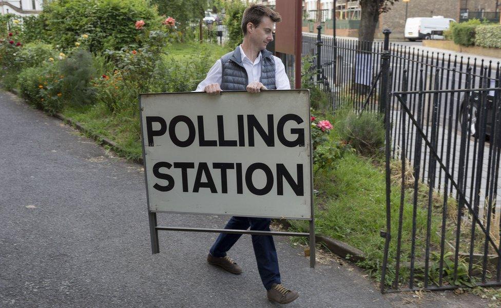 Man carrying a polling station sign