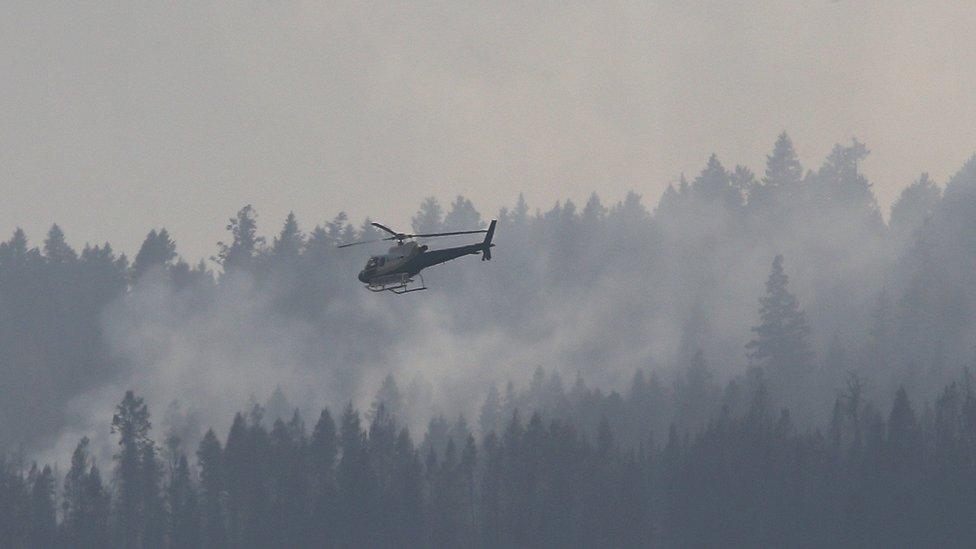 A helicopter flies over a wildfire south west of the town of Cache Creek, British Columbia, Canada July 18, 2017