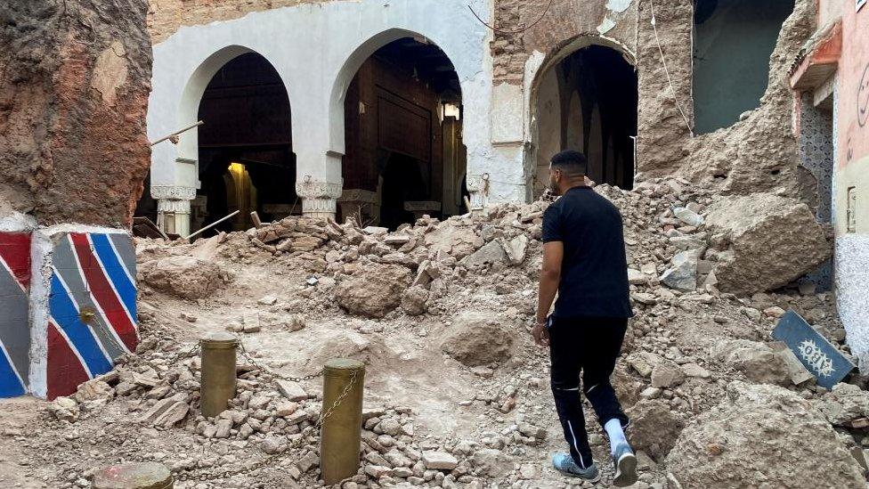 Man stands next to rubble of a former building in the old city