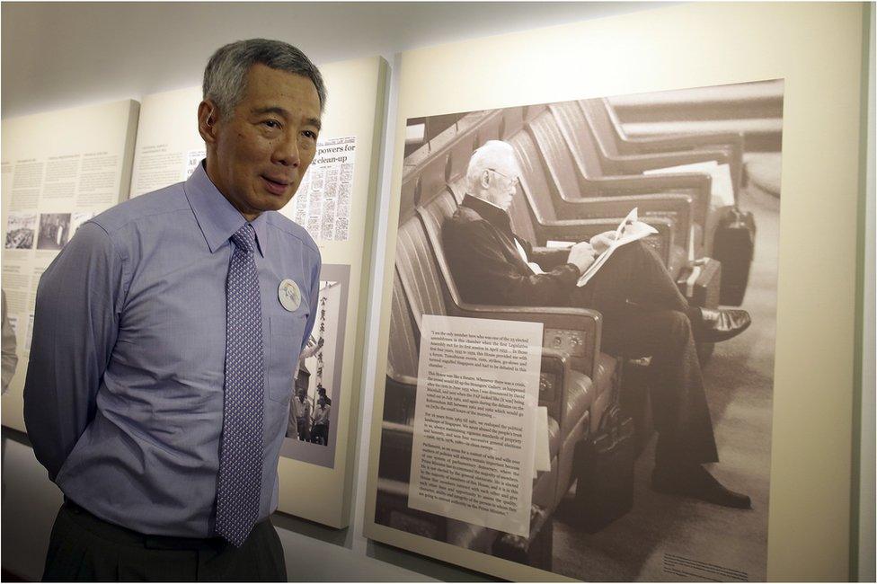 Singapore's Prime Minister Lee Hsien Loong walks past an old photograph of his father, the late Lee Kuan Yew during a remembrance ceremony held at the old Parliament House to mark the first death anniversary of Singapore's founding Prime Minister Lee Kuan Yew on Wednesday, 23 March 2016, in Singapore