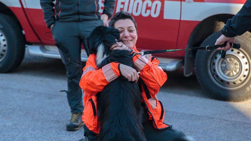 A woman cuddles a dog