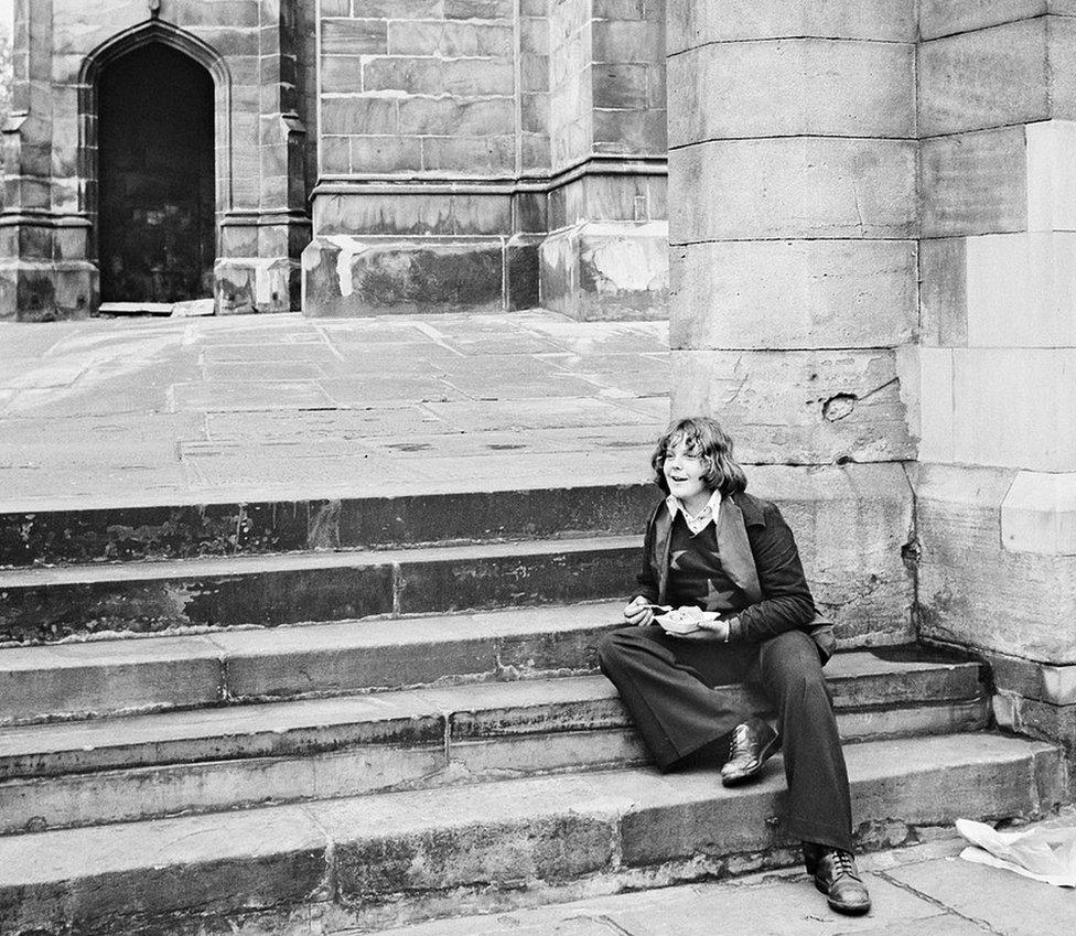 Teenager eats on steps outside an old building