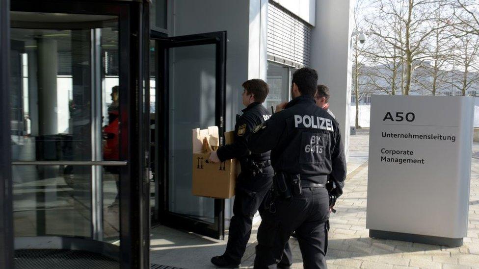 Policemen carry boxes as they search the headquarters of the German car manufacturer Audi