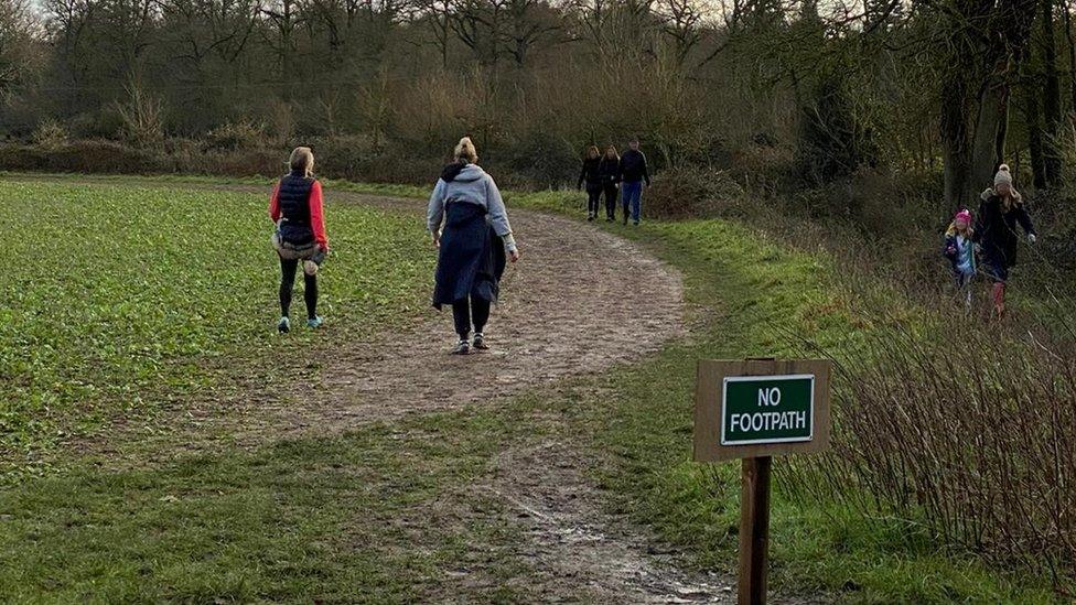 People walking off the footpath on crops