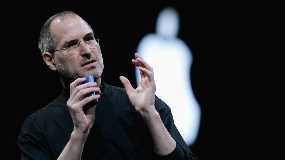 Steve Jobs gives a talk in front of an Apple logo