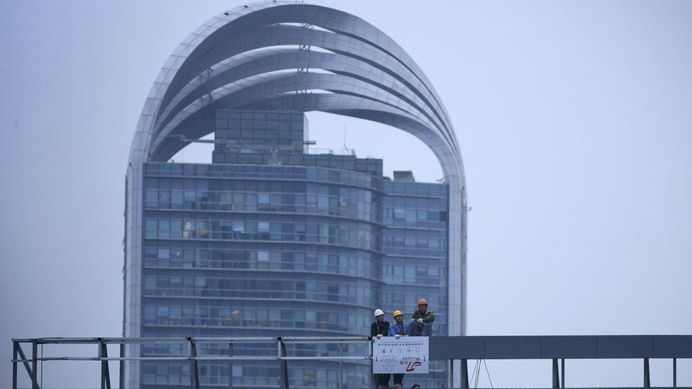 A group of workers look from the roof of a building in Shanghai