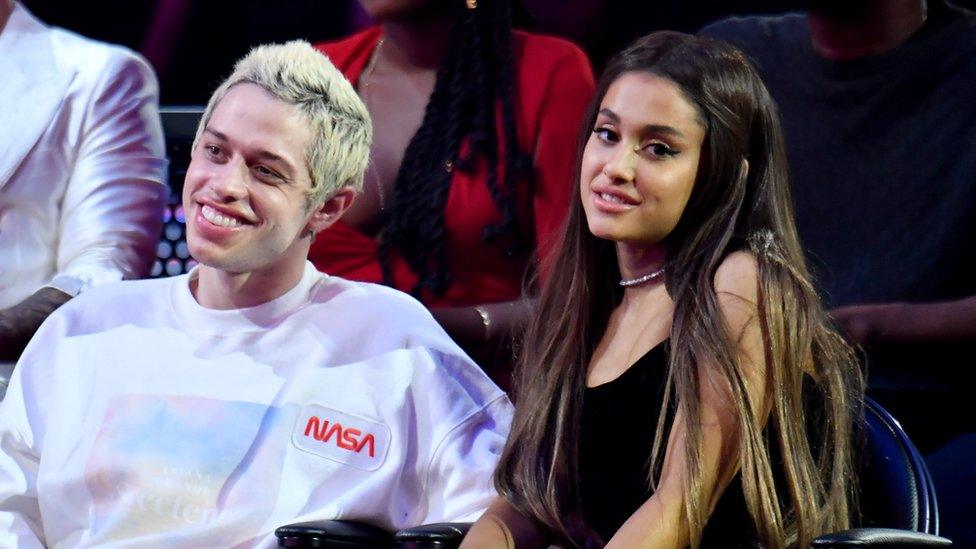 Pete Davison and Ariana Grande sit at event