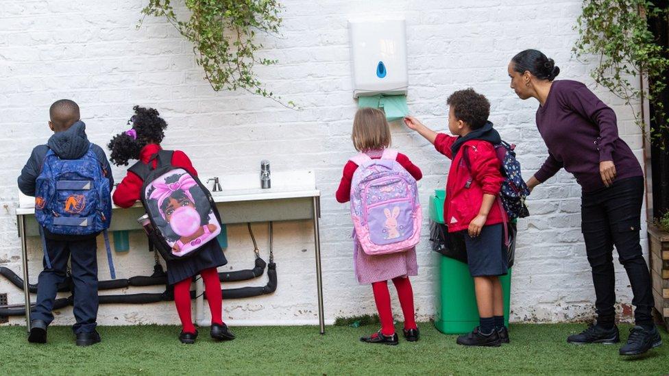 Pupils wash their hands as they arrive on the first day back to school at The Charles Dickens Primary School, last September