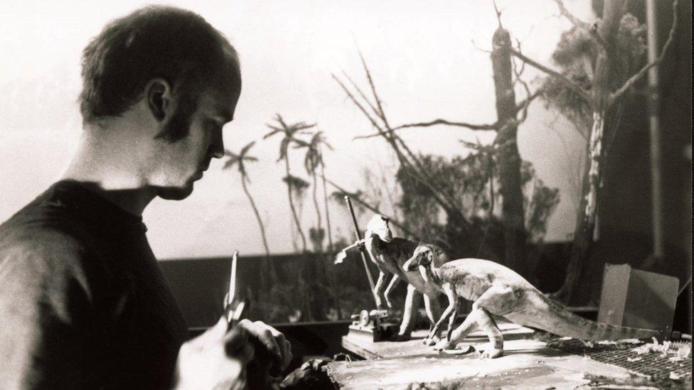 Black and white photo of a man working on dinosaur models