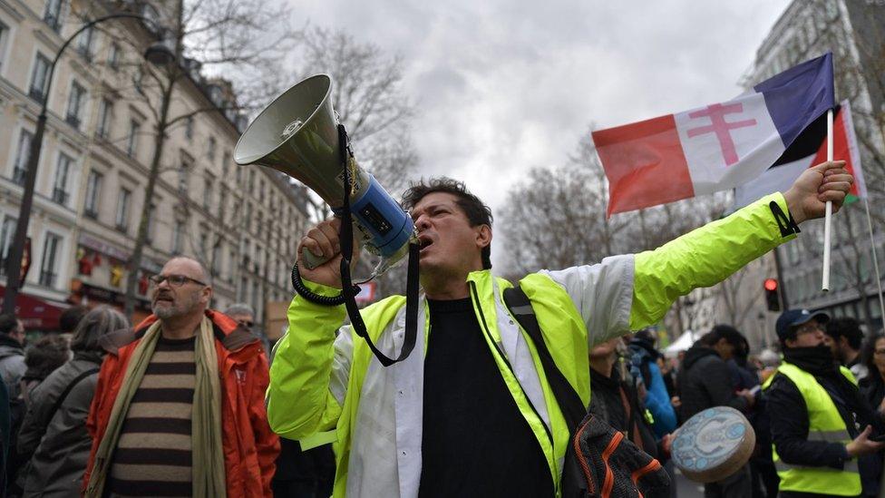 A protester waves a French flag and shouts into a megaphone in Paris